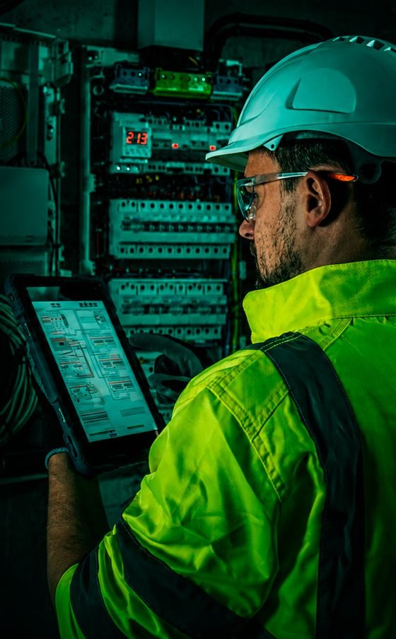 Técnico da Trimon inspecionando quadro de distribuição com tablet